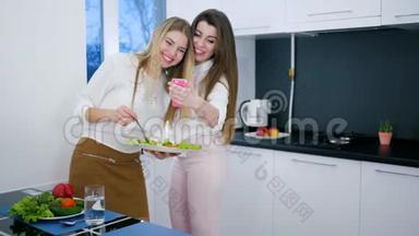 快乐的朋友们看着安卓系统上的照片，手里拿着饭菜站在厨房里